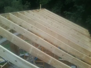 New roof rafters set over an addition before sheathing in Cranesville