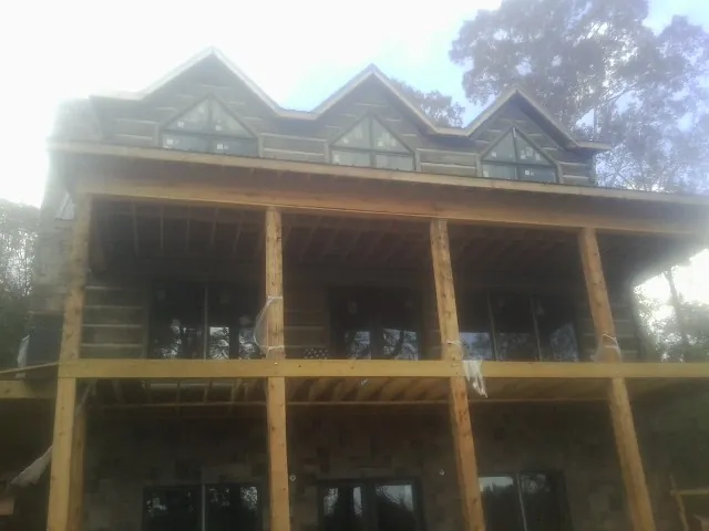 Dormers and porch framing on a large log home under construction — Roof Coating work by our crew in Cranesville