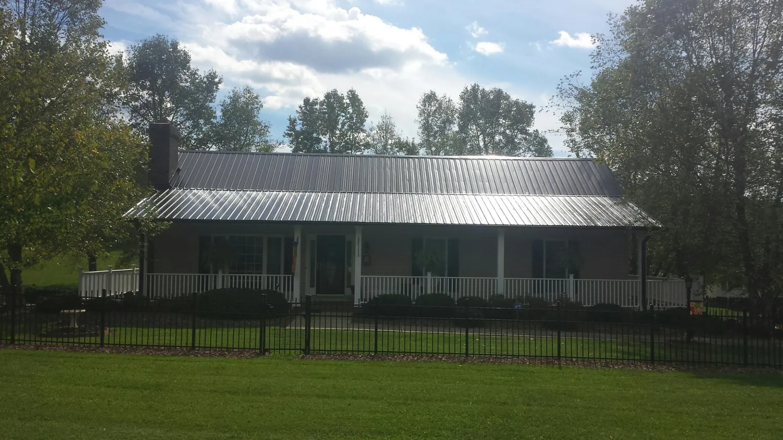 Gray metal roof on a brick ranch with a full width front porch — Gutter Guard Installation work by our crew in Cranesville