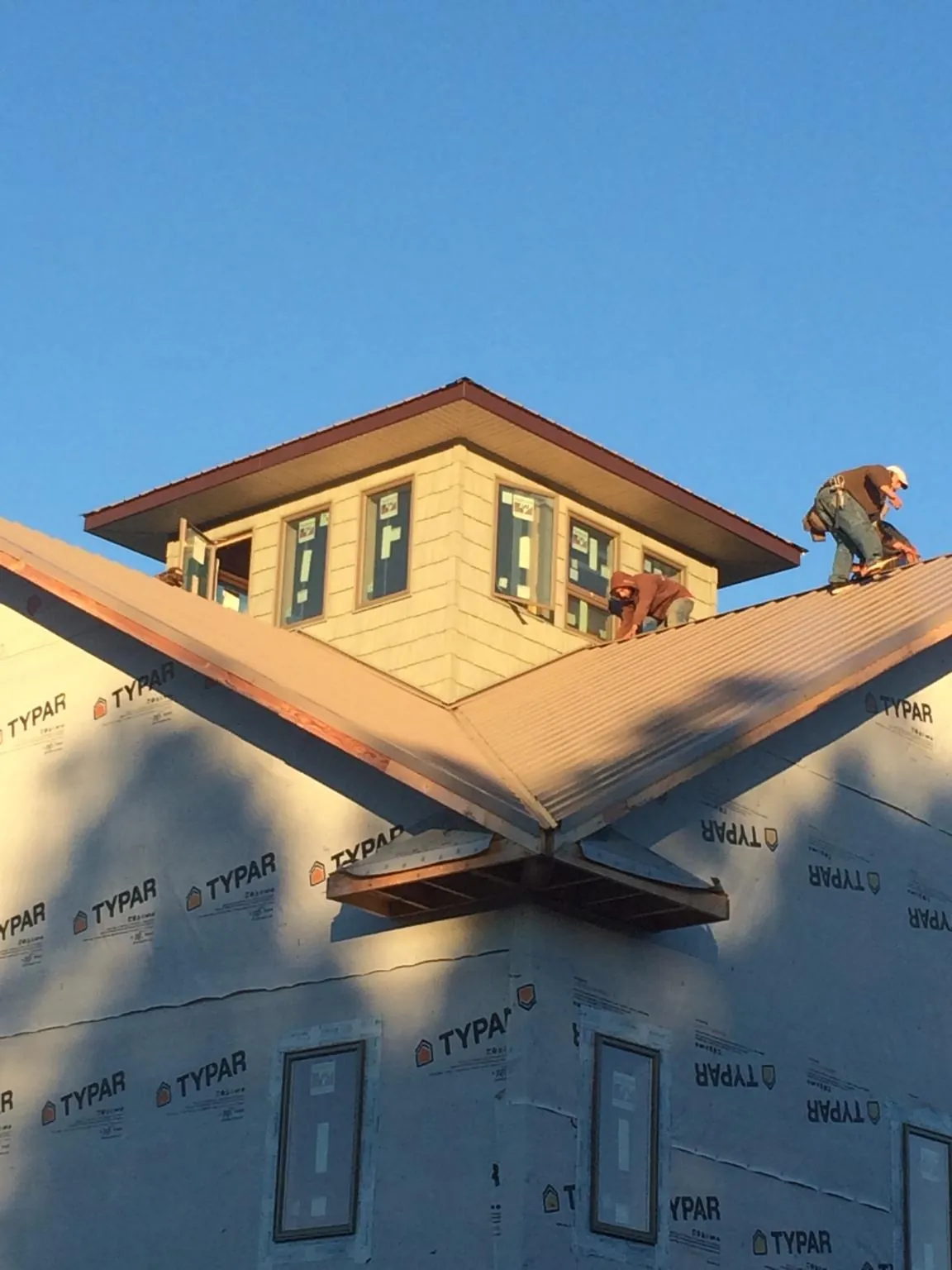 Roofers working around a rooftop cupola on a new metal roof at sunset — Roof Waterproofing in Cranesville by Roofing Brothers